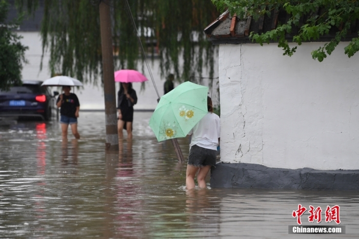 7月31日，市民行走在雨中的北京房山區(qū)瓦窯頭村。北京市氣象臺當日10時發(fā)布分區(qū)域暴雨紅色預(yù)警信號。北京市水文總站發(fā)布洪水紅色預(yù)警，預(yù)計當日12時至14時，房山區(qū)大石河流域?qū)⒊霈F(xiàn)紅色預(yù)警標準洪水。<a target='_blank' href='/'><p  align=