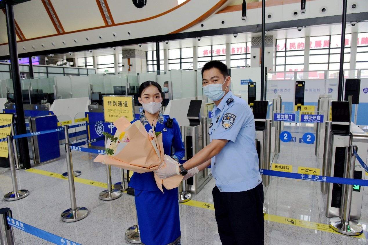 磨憨出入境邊防檢查站民警為中老鐵路第100萬(wàn)名出入境旅客，D888次國(guó)際旅客列車(chē)?yán)蠐爰藙?wù)員森達(dá)拉·妮緹婭（Sengdala Nitiya），送上鮮花。黃遠(yuǎn)飛 攝