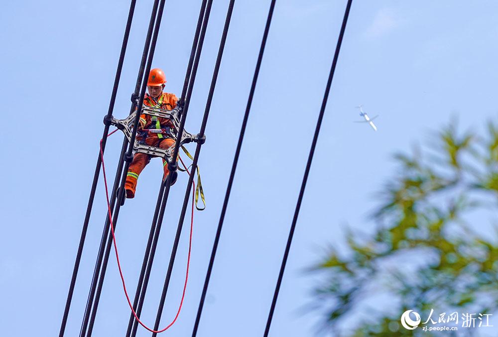 3月11日，在浙江省諸暨市河上鎮(zhèn)，浙江省送變電工程有限公司檢修人員在高空的導(dǎo)線上進(jìn)行線路檢修維護(hù)。人民網(wǎng) 章勇濤攝