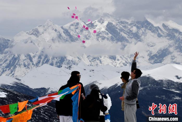 圖為5月14日，游客在西藏林芝色季拉山觀景臺(tái)拋灑“隆達(dá)”(風(fēng)馬旗，藏族民眾的一種祈福方式)。　李林 攝