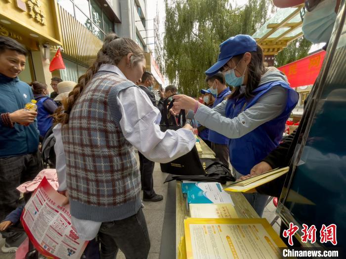 圖為志愿者為市民發(fā)放網(wǎng)絡(luò)安全宣傳手冊(cè)。　謝牧 攝